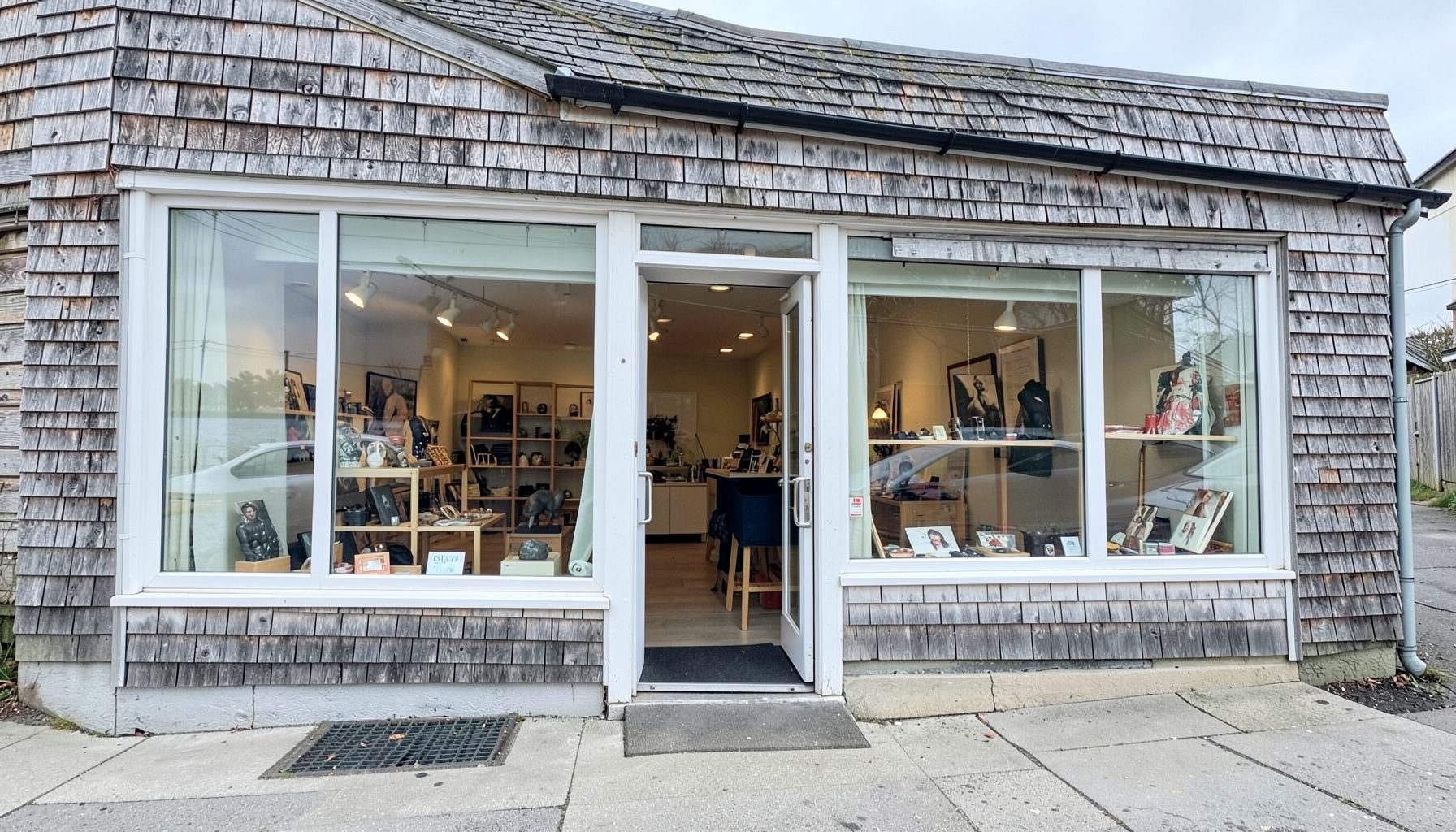 A coastal gallery shopfront with large windows and a weathered shingle exterior